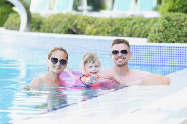 istock Young family with child in circle in pool on vacation 1368169113