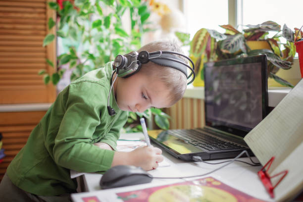 istock Distant education. Cute schoolchild studying homework during online lesson at home, social distance 1368171997