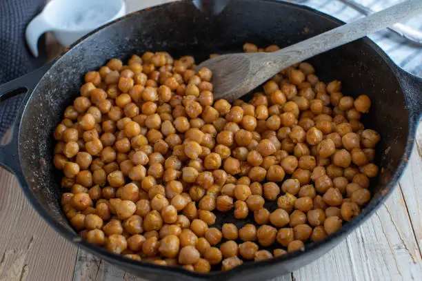 Delicious vegetarian plant based snack with spicy fresh roasted chick peas. Served in a rustic cast iron skillet with wooden spoon.