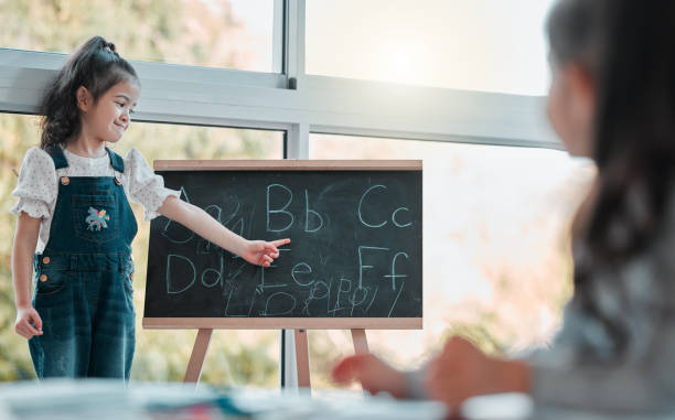 Shot of a young girl pointing at the letter B on a blackboard We're learning our ABC's today montessori stock pictures, royalty-free photos & images