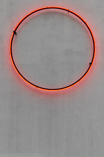 Neon ring. Pink neon circle on the gray wall with reflection. Copy space banner. Lights.