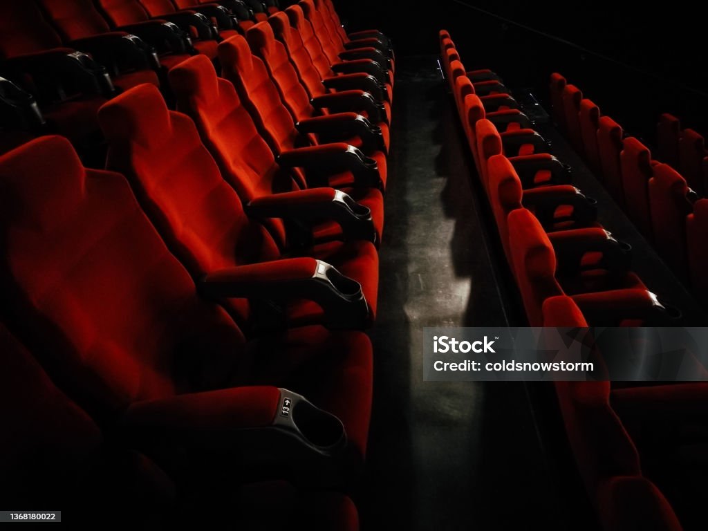 Rows of empty red seats at the movie theater Color image depicting rows of empty red seats inside a deserted cinema theater. Movie Theater Stock Photo