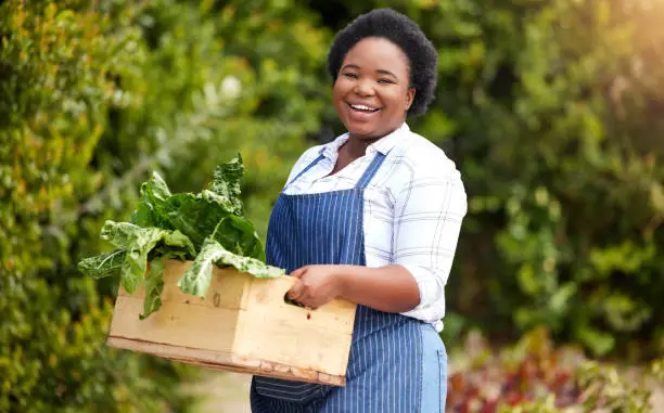 Photo of Shot of a young female farmer holding a crate on a farm