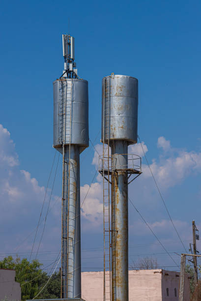 istock Two old style water towers surrounded by trees, with clear blue skies and clouds 1368180820