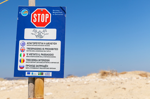 Zakynthos, Greece - August 16, 2016: Stop sign with text in different languages: Trespassing is Prohibited, nesting area loggerhead sea turtle