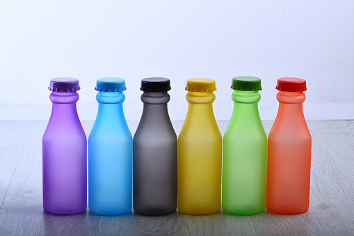 Colorful paint. Bottles with colorful dry pigments on white wooden background. Rainbow colors: choosing the right color. Colored beverages concept