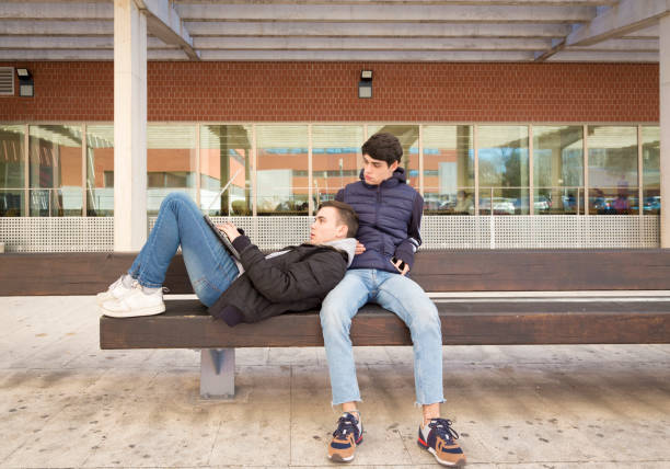 istock couple two gay university students together on a bench with laptop computer 1368183864