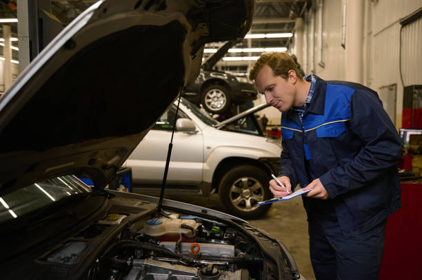 istock Young professional mechanic writes on clipboard while inspecting the engine of an automobile wit open hood in auto service repair shop 1368186449
