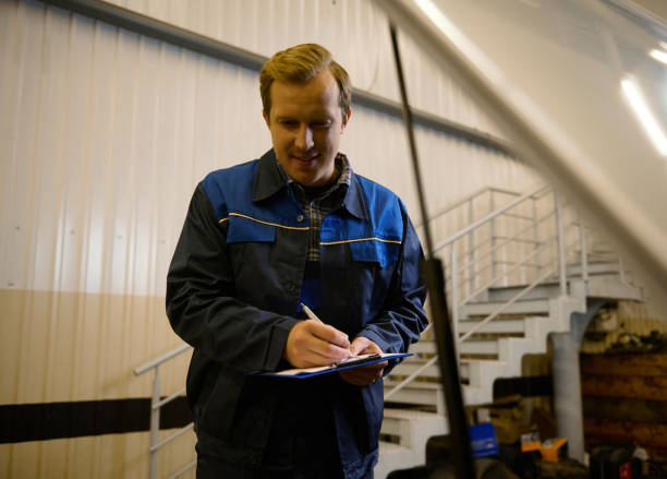 istock Portrait of auto mechanic, technician, car engineer in uniform making the checklist on clipboard for repairing automobile in the repair shop during warranty car maintenance. 1368187221