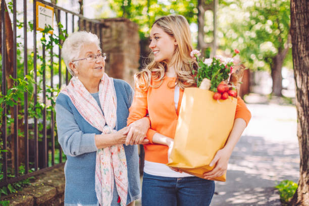 smiling granddaughter is doing shopping for her grandmother - volunteer senior adult teenager occupation imagens e fotografias de stock