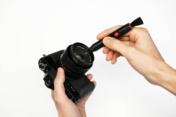 istock a man cleans a SLR camera with a brush from dust camera service front view 1368188572