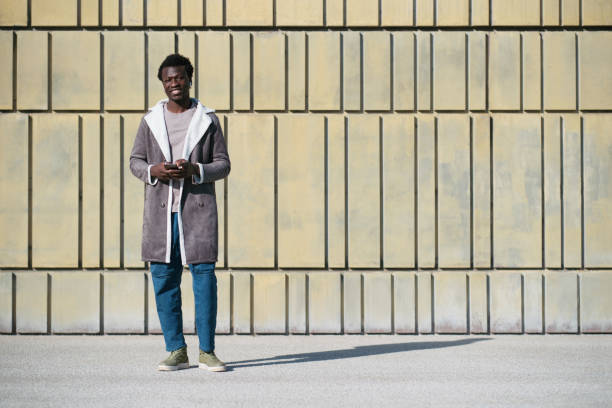 istock One young man stands outdoors with a smartphone in his hands. 1368189806