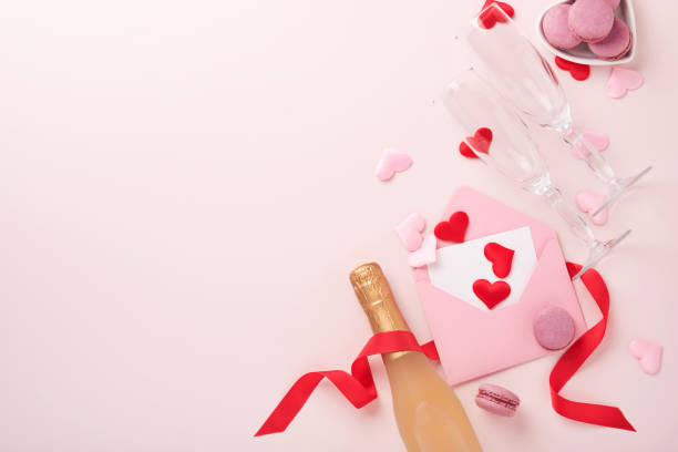 istock Valentines day greeting card with champagne bottle, gift box, red ribbon and envelope with blank note mockup inside on pink background. Top view with space for greetings. Greeting card with copy space 1368190627