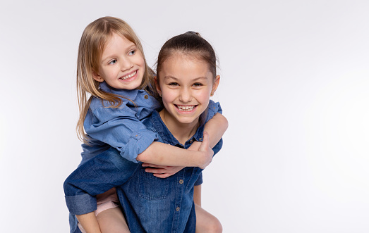 Two happy friends or sisters kid girls hugging. Together having fun and posing emotional on white background, happy smiling, friendship and relationship lifestyle people concept