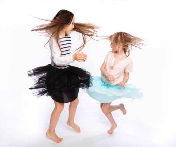 niños juguetones, concepto de tiempo de diversión. retrato de dos lindas niñas de 6 a 8 años con ropa ligera y bailando aisladas sobre fondo blanco. día de la madre, familia amorosa, concepto de infancia de paternidad - 8 9 years studio shot friendship sibling fotografías e imágenes de stock