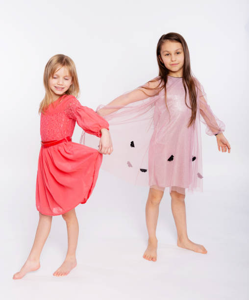 niños juguetones, concepto de tiempo de diversión. retrato de dos lindas niñas de 6 a 8 años con vestido rosa y bailando aisladas sobre fondo blanco. día de la madre, familia amorosa, concepto de infancia de paternidad - 8 9 years studio shot friendship sibling fotografías e imágenes de stock