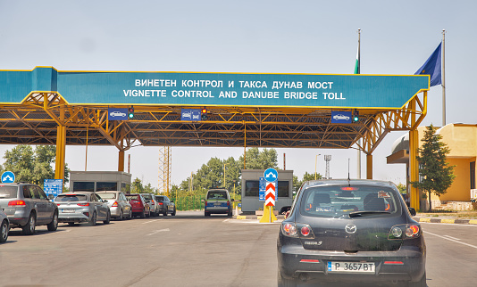 Ruse, Buylgaria - August 12, 2021: Line of cars stopped at customs vignette control and Danube bridge toll chekpoint crossing of the Bulgaria - Romania state border.
