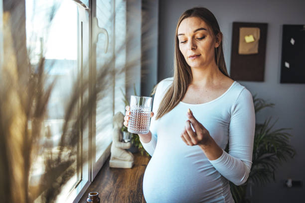 mujer feliz sostiene un vaso de píldora de agua, toma medicamentos diarios vitamina d - pill human pregnancy capsule women fotografías e imágenes de stock