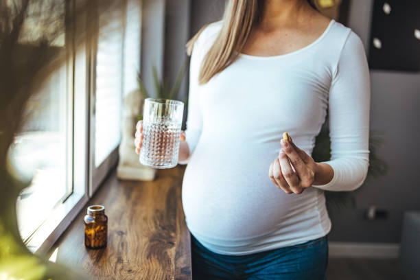 istock Pregnant woman is taking vitamin pill 1368196191