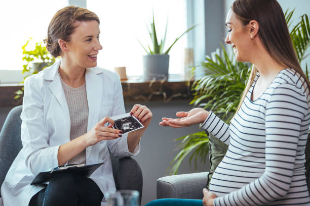 szczęśliwa kobieta w ciąży odwiedzić lekarza ginekologa w szpitalu lub klinice medycznej dla konsultanta ciąży. - human pregnancy midwife visit healthcare and medicine zdjęcia i obrazy z banku zdjęć