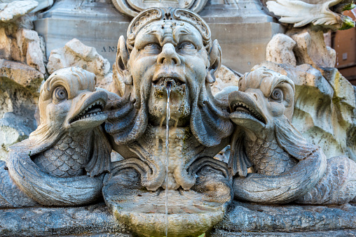 Rome, Italy - June 24, 2014: Fontana del Tritone meaning Triton Fountain, with people and cars in the background