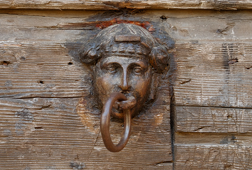 Old door knocker on weathered wooden door