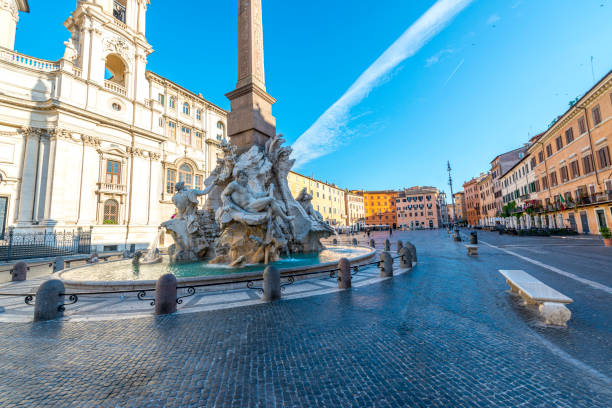 Rome, Italy, Fountain at Piazza Navona Piazza Navona, with the Moor Fountain in the background and the rays of the rising sun reflecting from the church of Sant'Agnese in Agone, the Fountain of the Four Rivers with it's obelisk in the foreground. fontana del moro stock pictures, royalty-free photos & images