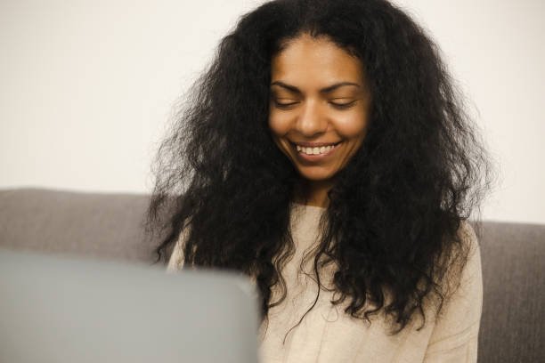istock Happy black woman working on computer at home. Cheerful entrepreneur person doing distant work online. Young adult African female typing on notebook pc with toothy smile 1368205417