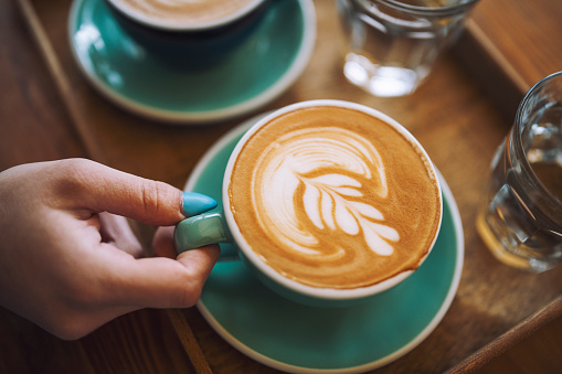 Mujer sosteniendo una taza de café con leche en el café. photo