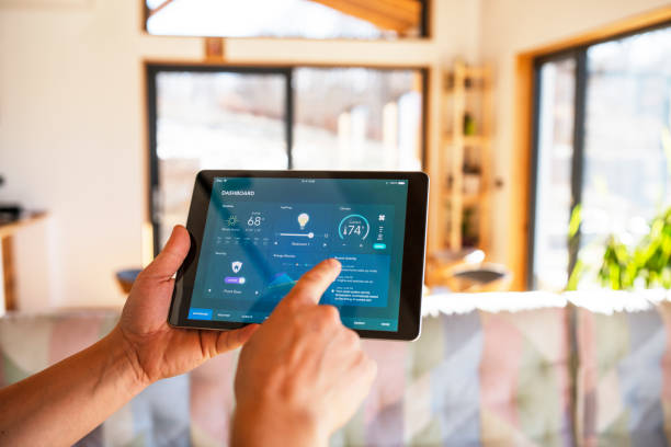 mann mit tablet mit smart-home-steuerungsfunktionen zu hause. - smarthome stock-fotos und bilder