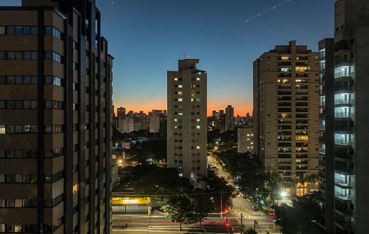 Sunset in the city of São Paulo. Campo Belo and Brooklyn district. Traffic lights on  José Diniz avenue. In the blue sky, lights and a plane's path.