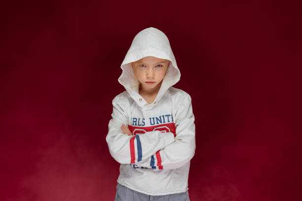 rebellious stubborn or pissed off young teenage girl with crossed arms in a hoodie stock photo
