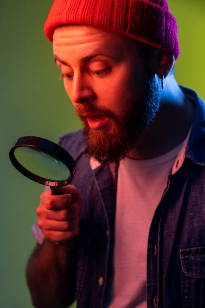 istock Hipster guy looking through magnifying glass, spying, finding out something, exploring, inspecting. 1368213200