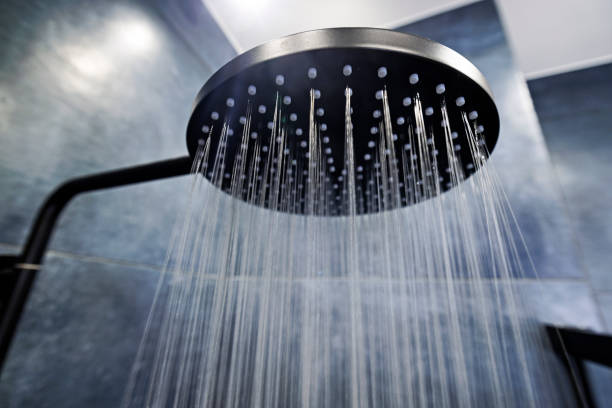 water running from a black rain shower head - douche stockfoto's en -beelden