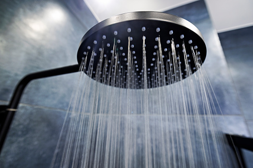 Modern luxury bathroom. Water running from a black rain shower head.\nCanon R5.