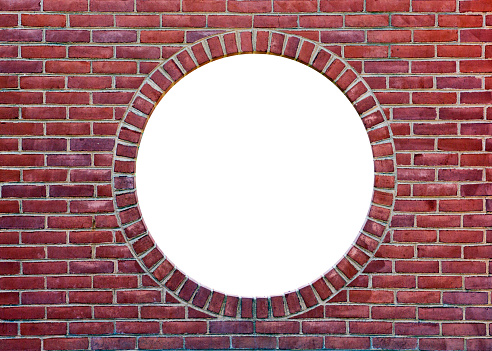A brick wall with a round opening showing blank white area available for text