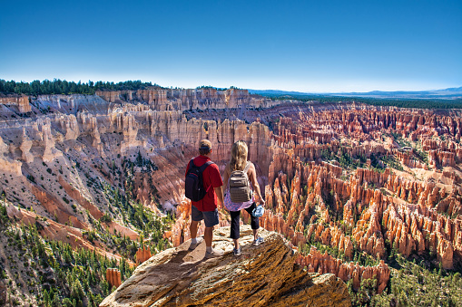People relaxing on summer vacation hiking trip. Couple looking at beautiful  mountain view. Friends standing on the top of the mountain. Inspiration Point, Bryce Canyon National Park, Utah, USA