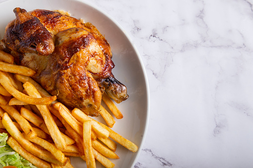 Grilled chicken with french fries and salad on a marble table. Top view with copy space.