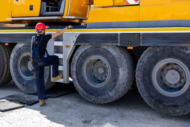 młody budowniczy wchodzi do maszyny budowlanej na placu budowy. - construction equipment large construction crane zdjęcia i obrazy z banku zdjęć