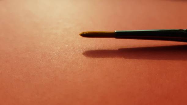 istock new paint brush on red sunny table, side view, closeup. 1368218542