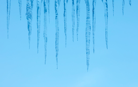 Close-up of icicles on a blue sky background. Space for copy.