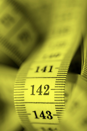 Close-up of a yellow tape measure. Shallow depth of field, space for copy.