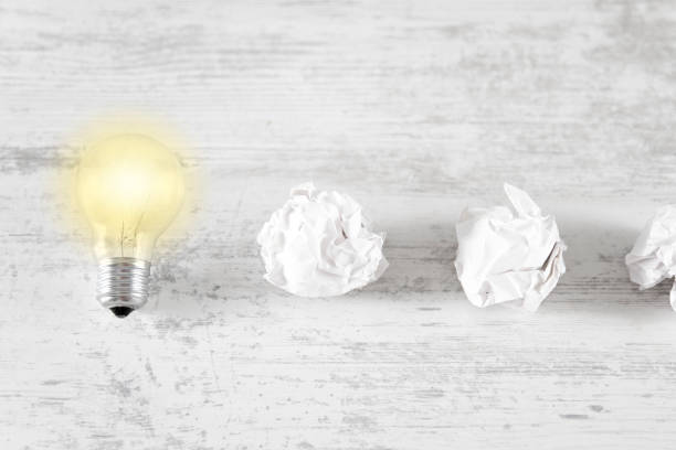 New idea concept with paper and light bulbs on white wooden background