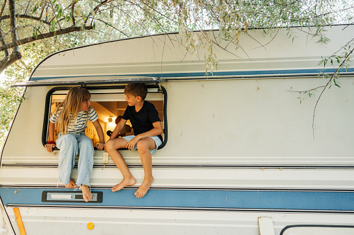 Photo of sister and brother at the camper van window during their vacation