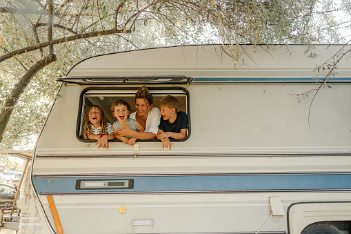 Photo of smiling mother and her children in their camper van during vacation