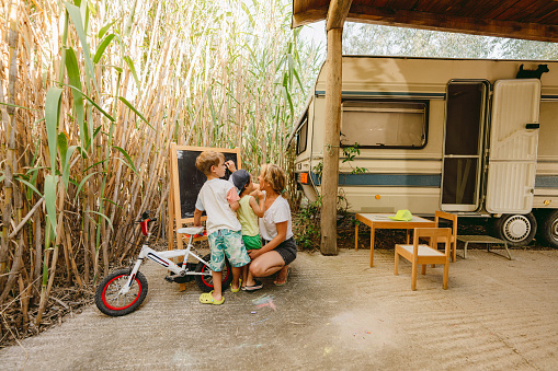 Photo of little boys learning to write during their RV vacation. Their mother is teaching them.
