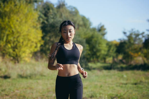 公園で午前中に走る美しいアジアの女性、暗いスポーツスーツを着た女性 - 女性ランナー ストックフォトと画像