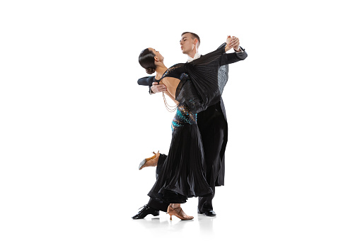Professional performance. Young couple, man and woman dancing tango isolated on white studio background. Artists in black stage costumes. Concept of art, beauty, action, emotions. Copy space for ad