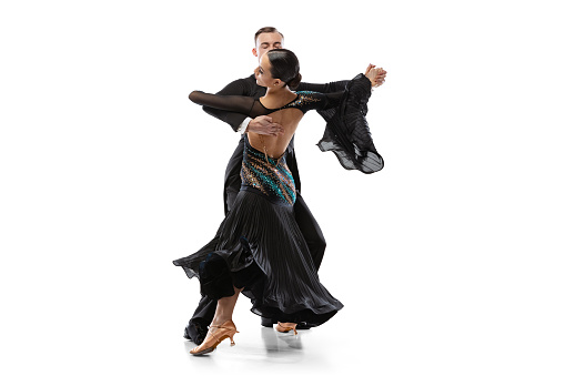Beautiful sportive man and woman practising ballroom dancing isolated on white studio background. Artists in black stage costumes. Concept of art, beauty, grace, action, emotions. Copy space for ad