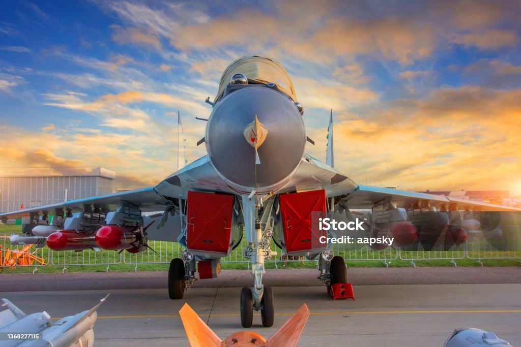 Fighter with covered engines and live ammunition on the wings in the parking lot during sunset. Fighter with covered engines and live ammunition on the wings in the parking lot during sunset Air Force One Stock Photo